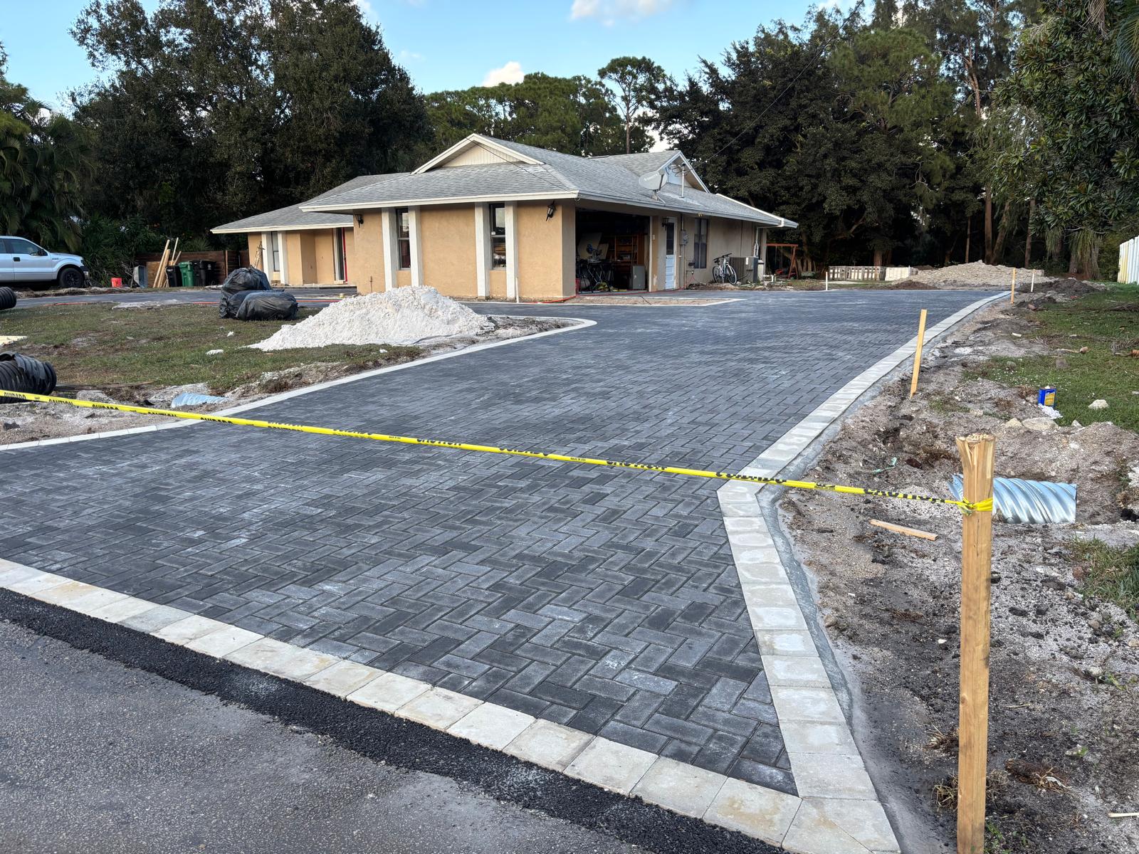 New charcoal herringbone paver driveway with curved curb