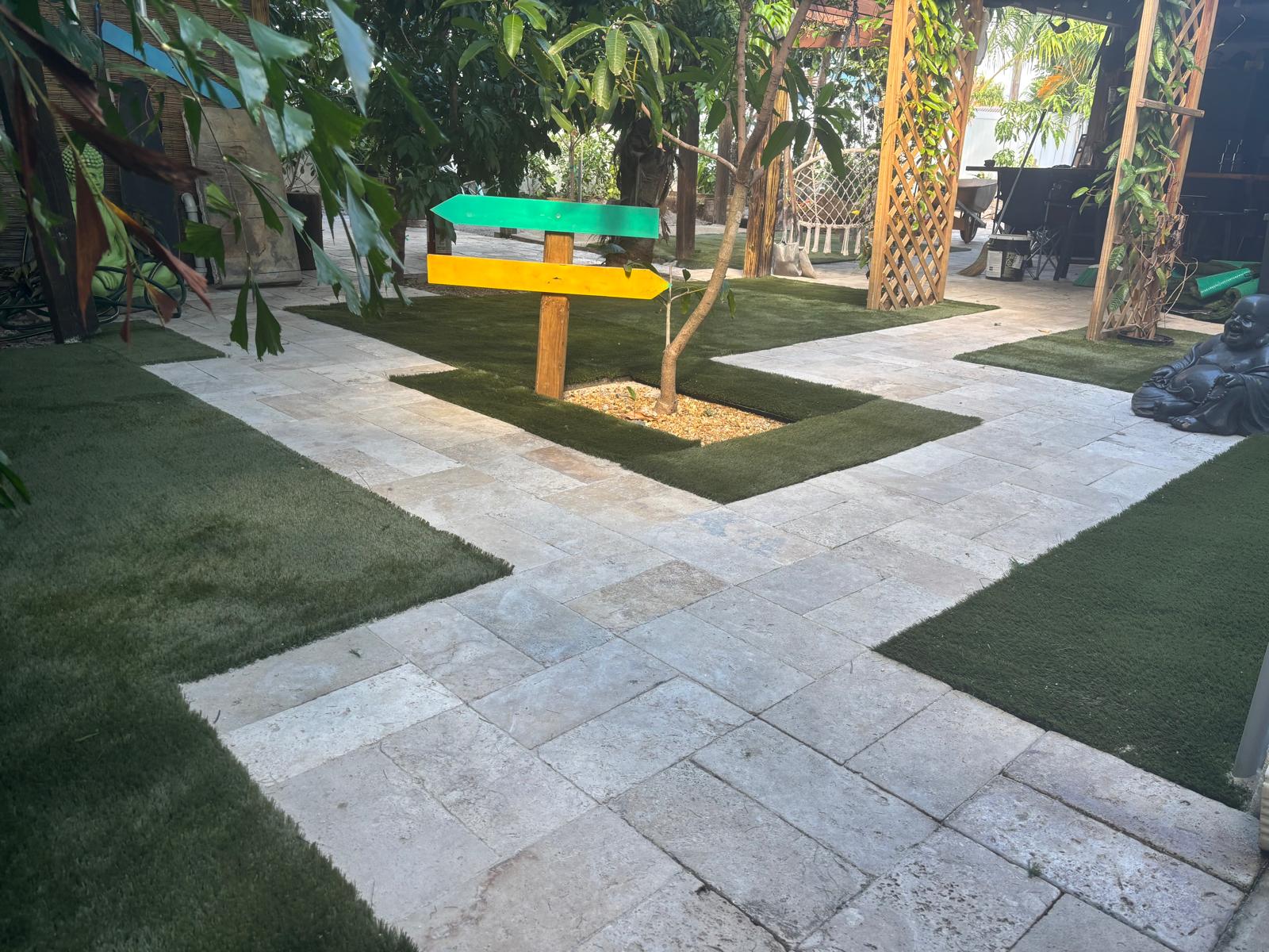 Travertine pavers with artificial grass inlays in a garden