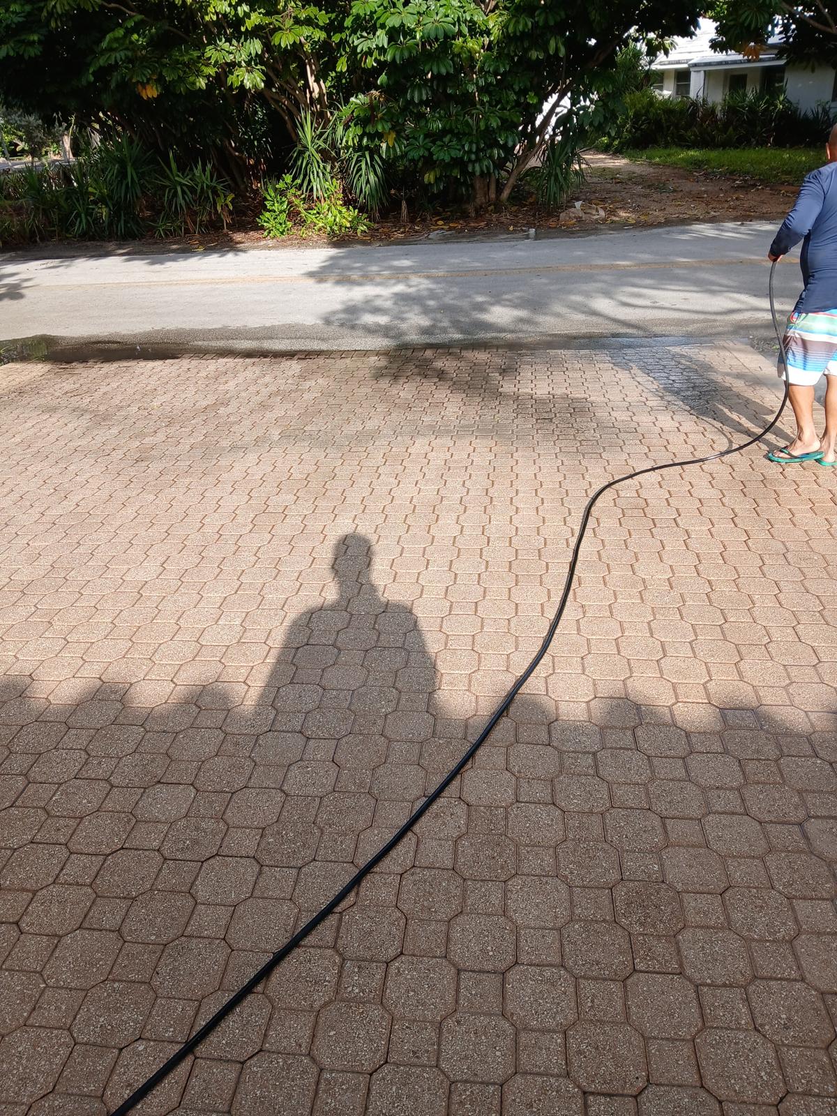 Pressure washing a paver driveway — half clean, half dirty